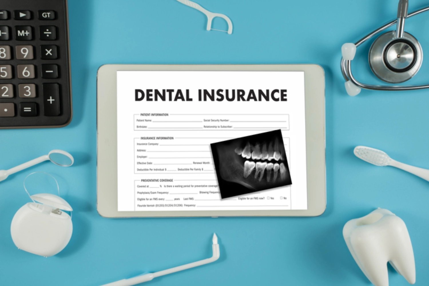 Dental insurance form with dental X-ray on a clipboard.