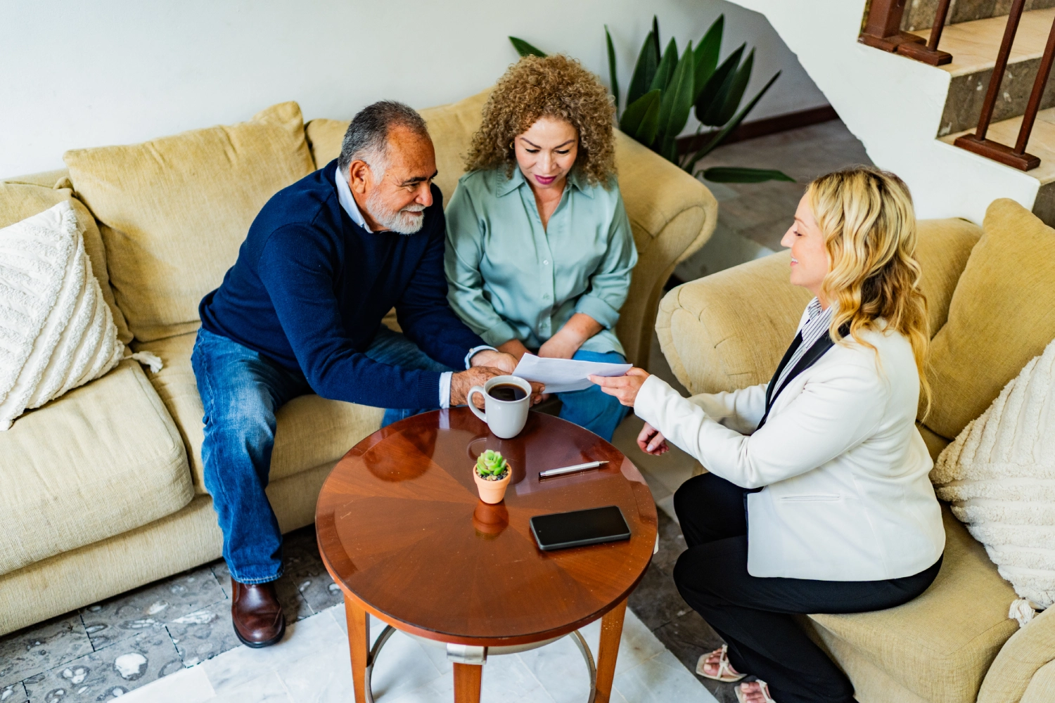 Three people having a friendly meeting around a coffee table.